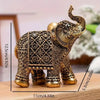 A vintage resin elephant ornament with gold detailing, displayed on a wooden surface.