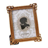 A gold-framed photo frame with a vintage European design featuring a white background and an engraved silhouette.