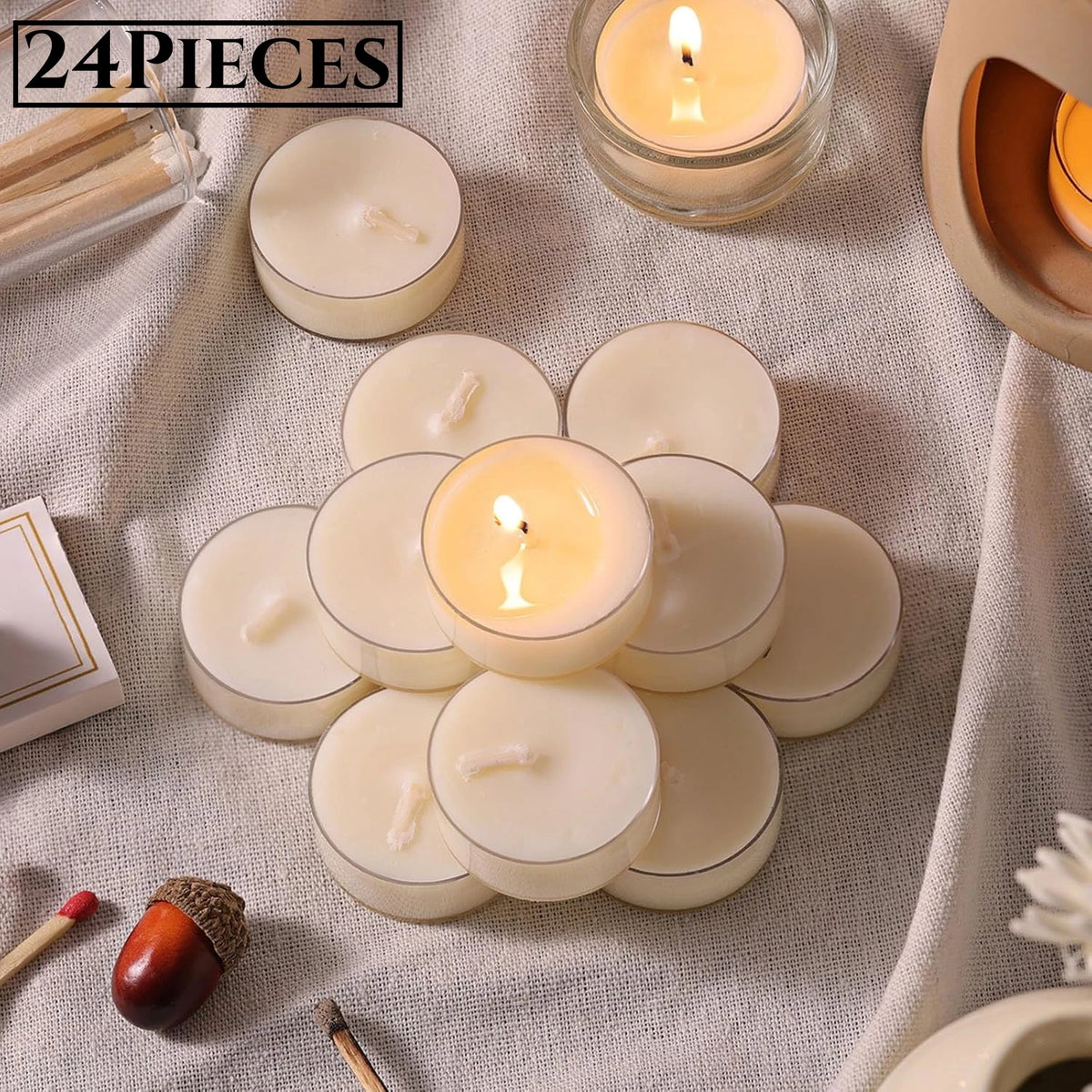 A collection of natural beeswax tealight candles in various sizes and a wooden stick are displayed on a light fabric.