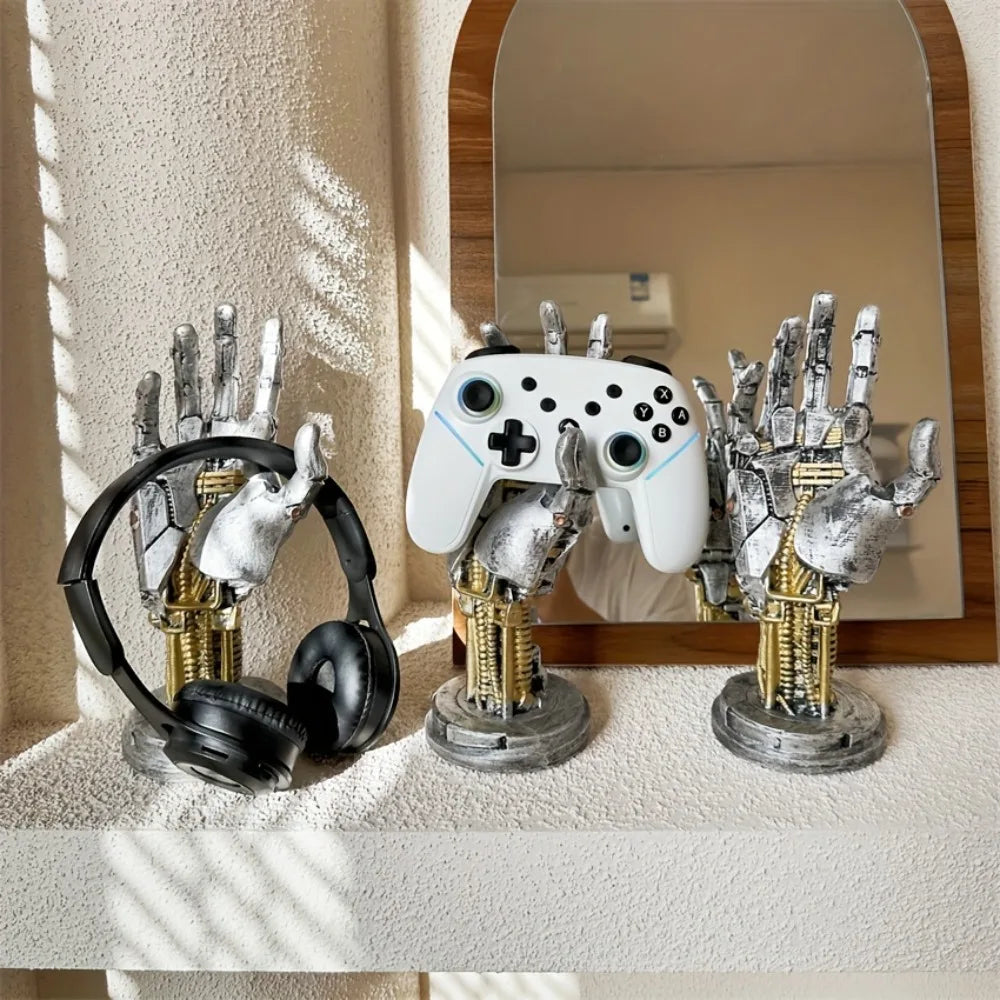 A silver robotic hand and a white game controller are displayed on a shelf next to a black headset.
