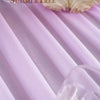 A close-up of lilac sheer chiffon fabric draped softly, with white flowers visible in the foreground.