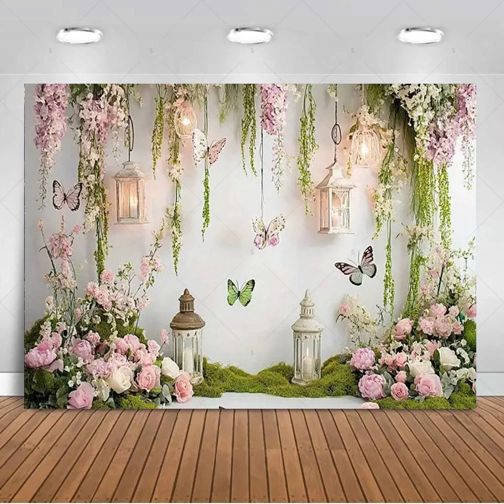 A floral and butterfly photo backdrop featuring pink and green foliage, hanging lanterns, and soft lighting.