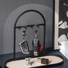 A black wrought iron key holder rack displaying several keys on a light-colored desk organizer tray.