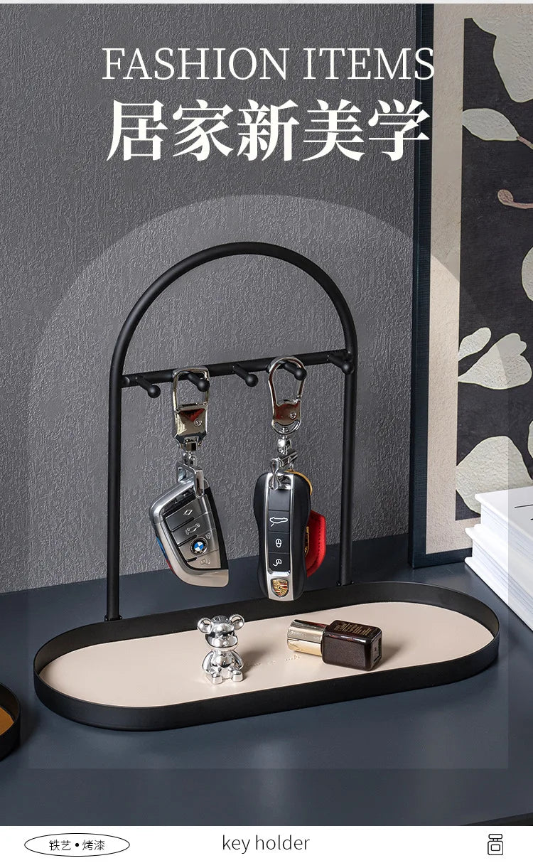 A black wrought iron key holder rack displaying several keys on a light-colored desk organizer tray.