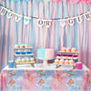 A pink and blue gender reveal party table decorated with bunting, cupcakes, and balloons.