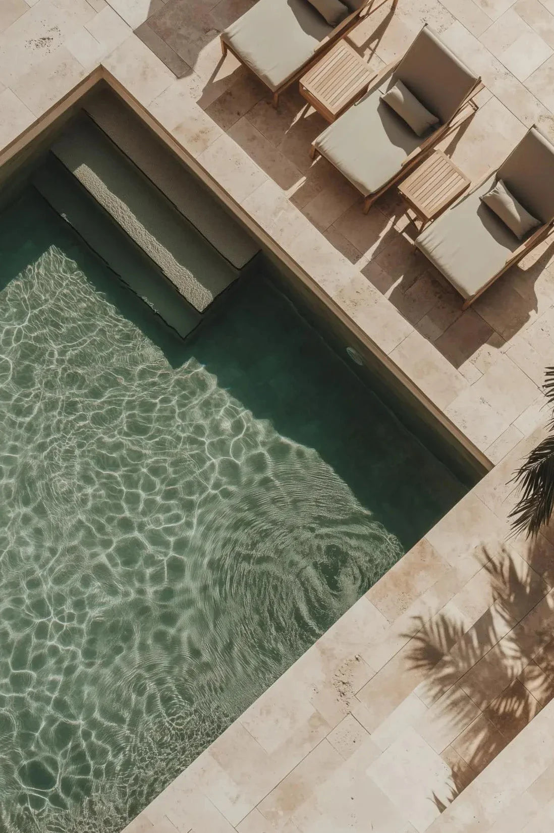 A close-up view of a swimming pool with sunlight dappling through the water and surrounding stone paving.