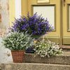 A bouquet of purple and white artificial flowers displayed on stone steps against a yellow building facade.