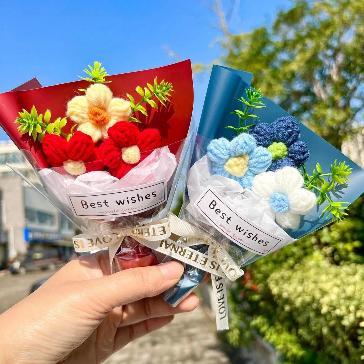 A hand holds a bouquet of handmade crochet sunflower mini flowers in colorful paper wrapping.