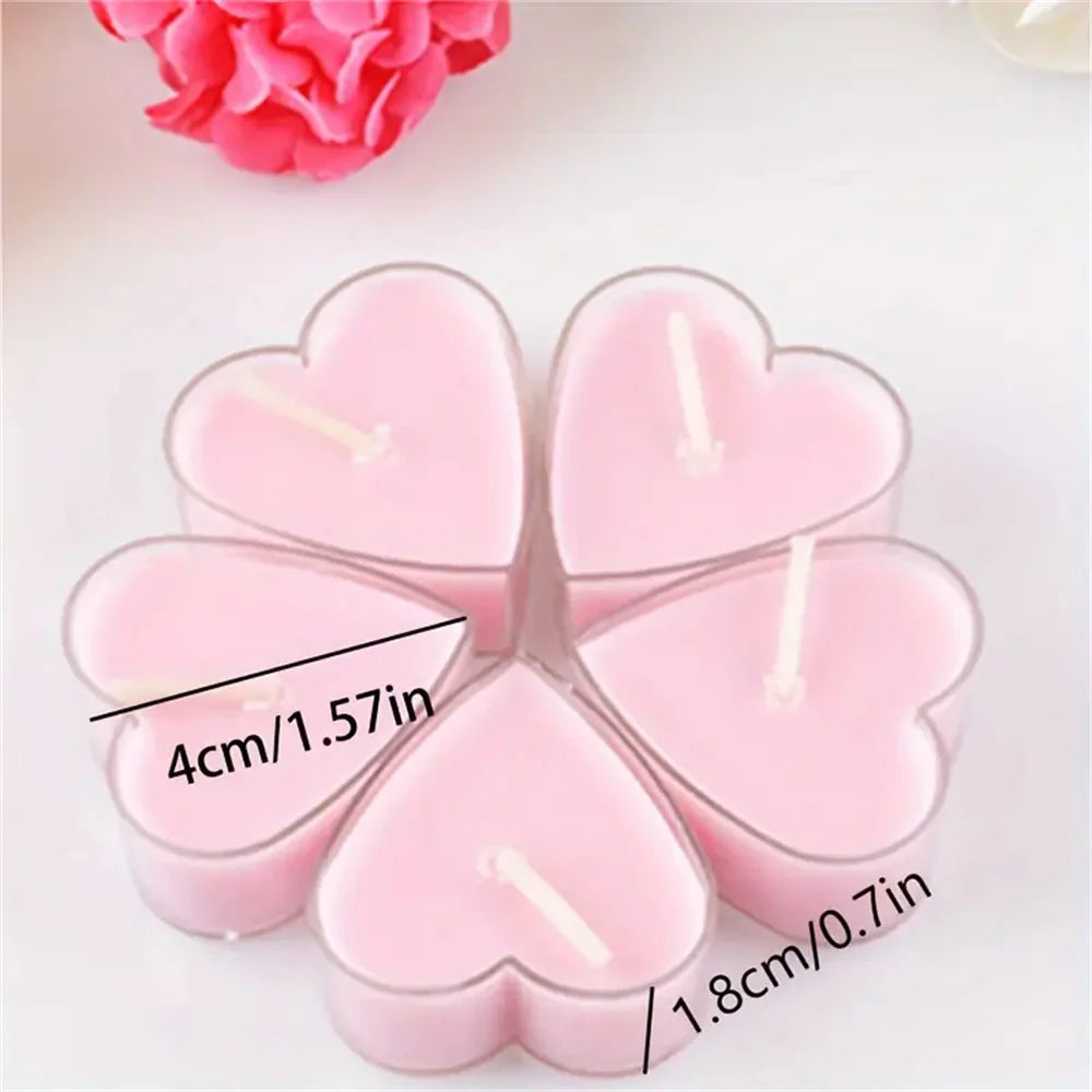 Un set de quatre bougies parfumées en forme de cœur roses arrangées sur une surface blanche.