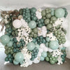 A dense arrangement of sage green and white latex balloons forming a floral backdrop for parties and events.