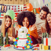 A group of people celebrating with a colorful foam ball cake and various decorations on a table.