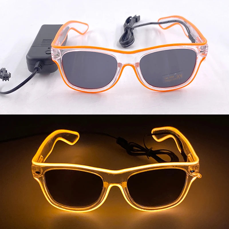 Pair of orange light up EL wire party glasses resting on a white surface and a dark background.