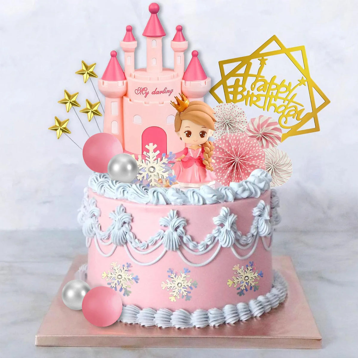 A pink princess castle cake topper set featuring a castle, stars, and a golden birthday banner on a tiered cake.