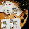 A collection of magnetic mini photo frames and various small cameras are arranged on a wooden surface.