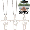 Three stainless steel praying hands cross pendants displayed with a hand for scale