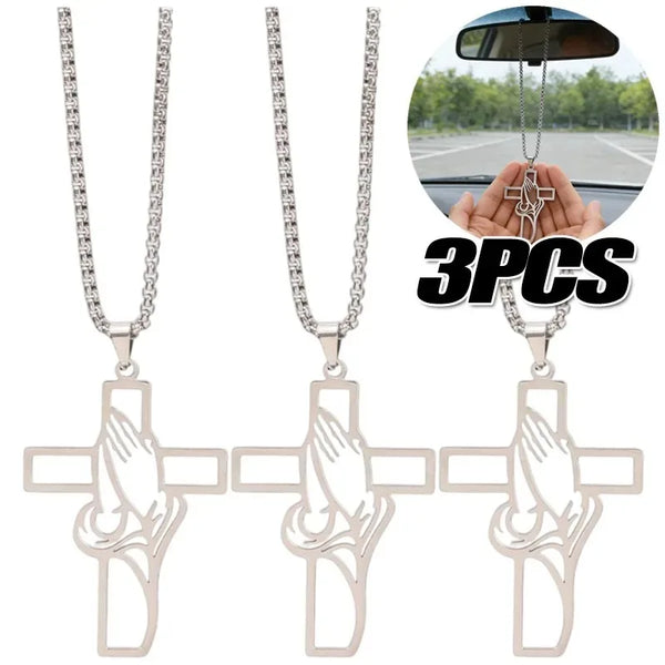 Three stainless steel praying hands cross pendants displayed with a hand for scale