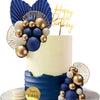 A tiered cake decorated with blue and gold spherical balloons and feather toppers on a white background.