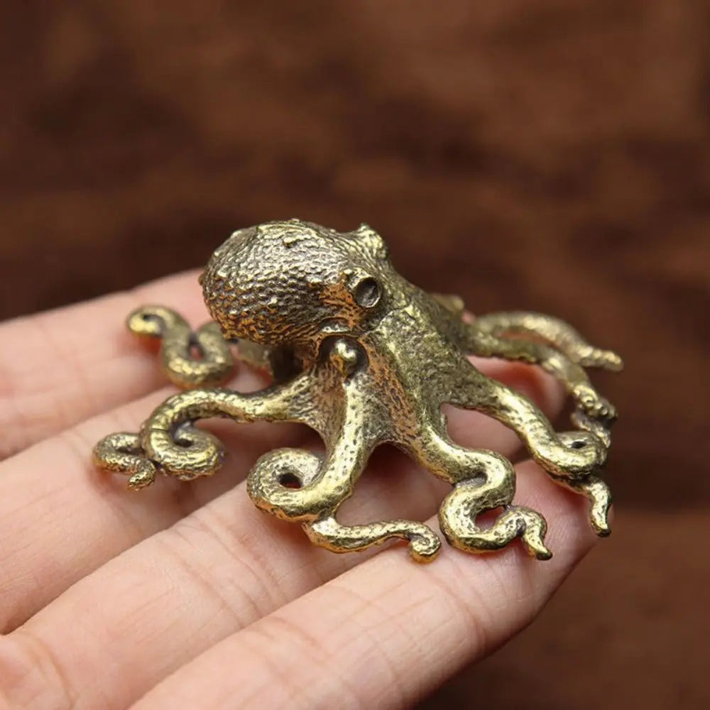 Antique brass octopus desk ornament resting on a hand