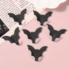 A set of five black gothic bat adhesive hooks for keys and bags displayed on a pink background.