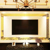 A rectangular black screen is framed by a gold decorative border on a wall, with a dark table in the foreground.