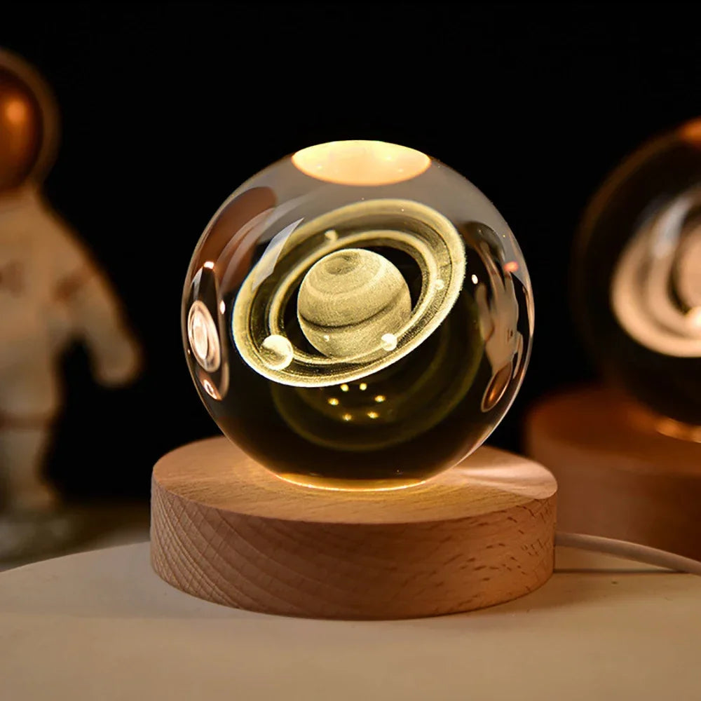 A glass crystal ball night light with a golden glow rests on a wooden base against a dark background.