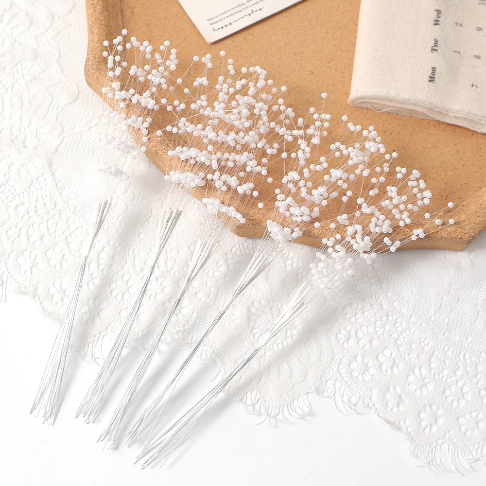 White pearl string beads arranged in a spray on a brown wooden surface with sheer white lace.