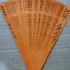 Hand carved bamboo folding fan with intricate cutouts in a warm orange-brown color.