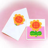A pink envelope and a square thank you card featuring a yellow flower design.