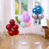 A display of colorful balloons in various shades of pink, purple, and blue arranged on adjustable stands.