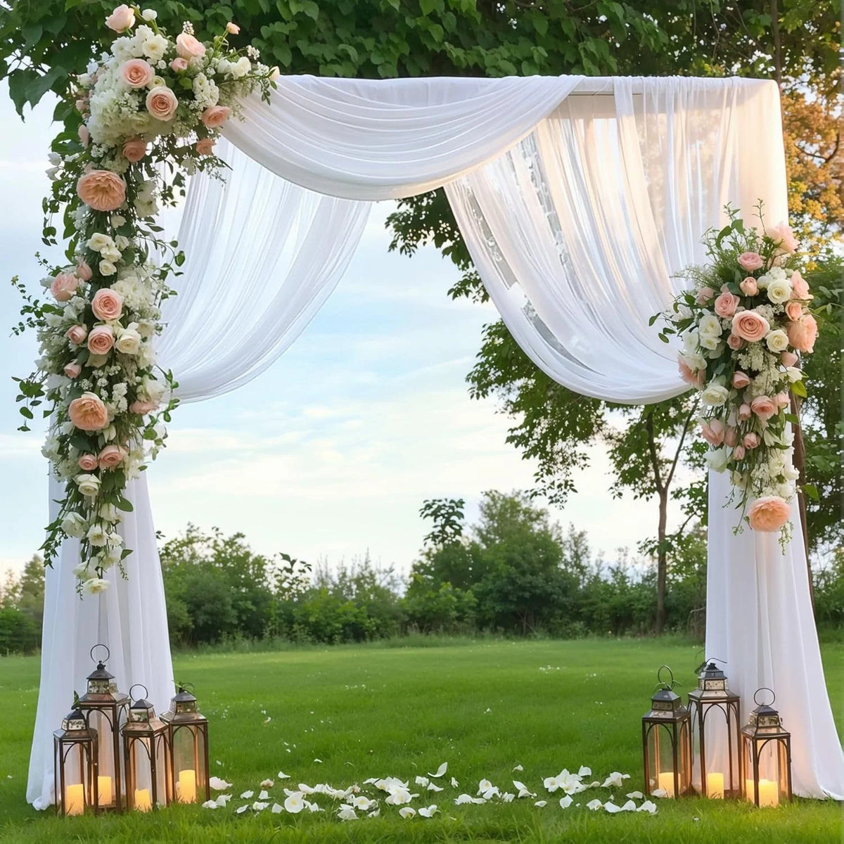 Tissu chiffon blanc élégant formant un décor d'arche pour un événement extérieur.
