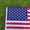 A double-sided American flag with stars and stripes displayed on green grass.