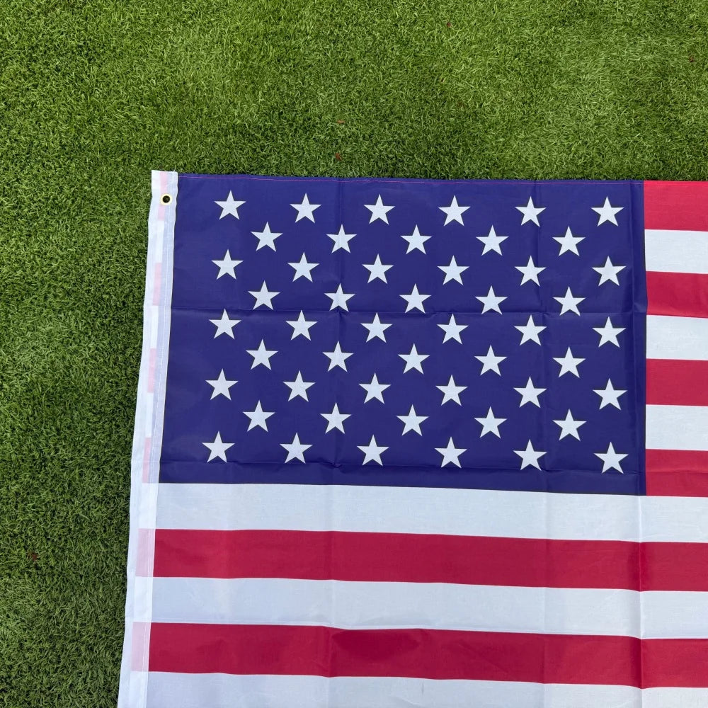 A double-sided American flag with stars and stripes displayed on green grass.