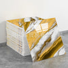 Gold and white marble pattern faux self-adhesive wall tiles displayed on a gray surface.
