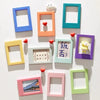 A set of five decorative photo frames in various colors, including blue, orange, green, purple, and pink, with small heart ma