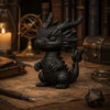 Figurine sombre de dragon avec cornes assis sur du parchemin vieilli, à côté de livres et d'une boussole.