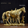A gold-colored sculpture of a horse standing next to a wooden fence, displayed on a base.