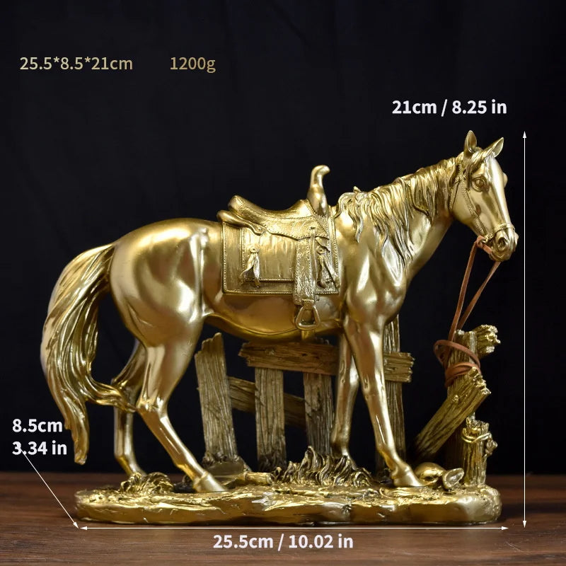 A gold-colored sculpture of a horse standing next to a wooden fence, displayed on a base.