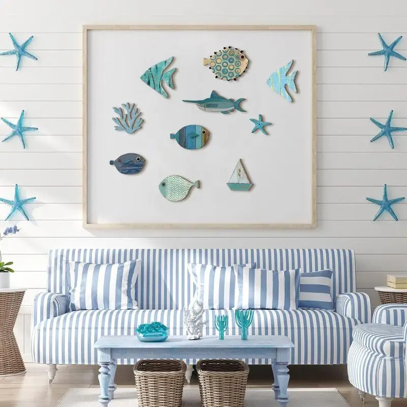 A set of ten wooden hanging fish decorations in various shades of blue and teal displayed on a white wall above a striped sof
