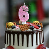 A birthday cake decorated with pink glitter number six candles and fruit slices
