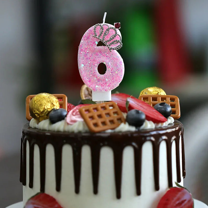 A birthday cake decorated with pink glitter number six candles and fruit slices