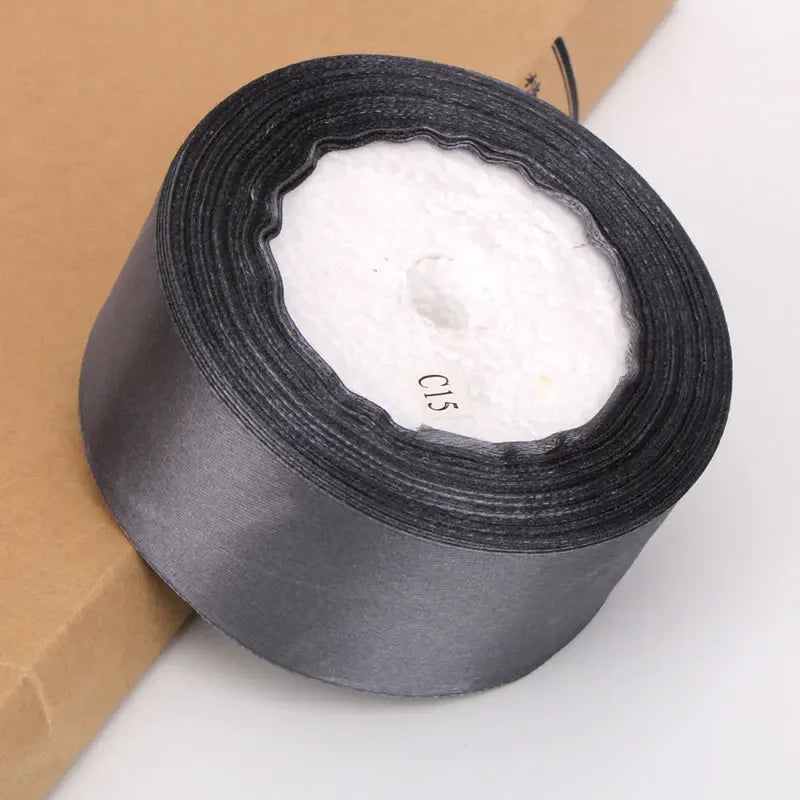 Roll of white satin ribbon for crafts and gift wrapping, packaged in brown paper.