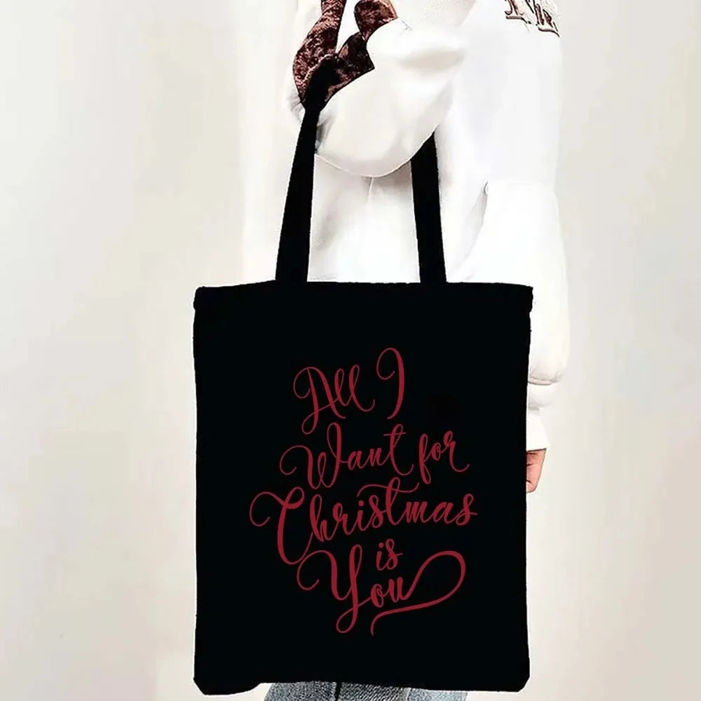 Black tote bag with pink script text that reads All I want for Christmas is you
