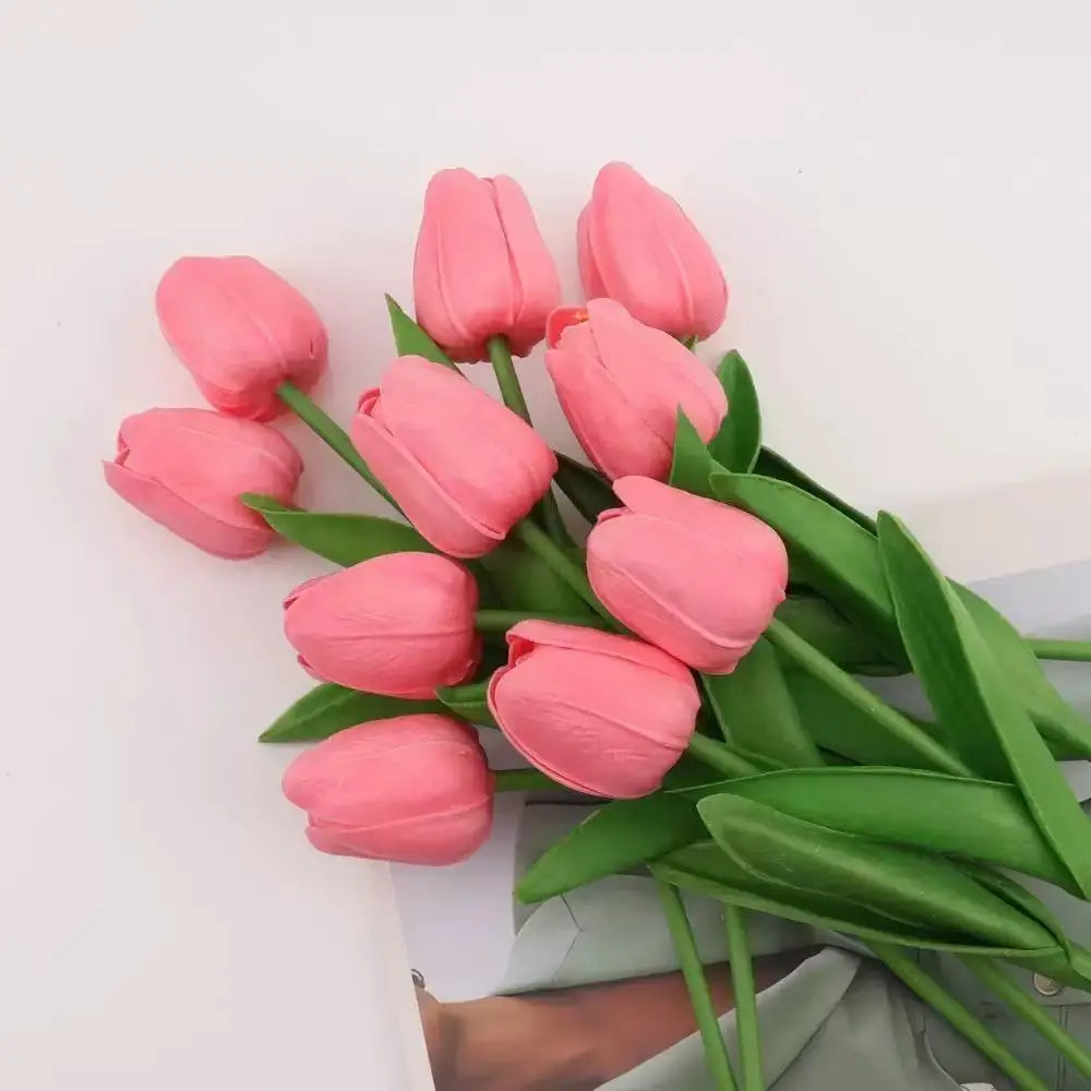 A bouquet of pink artificial tulips with green leaves arranged for home or wedding decor.
