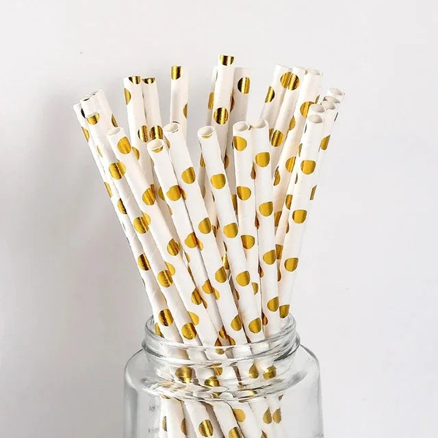 A glass jar filled with disposable party straws decorated with gold polka dots.