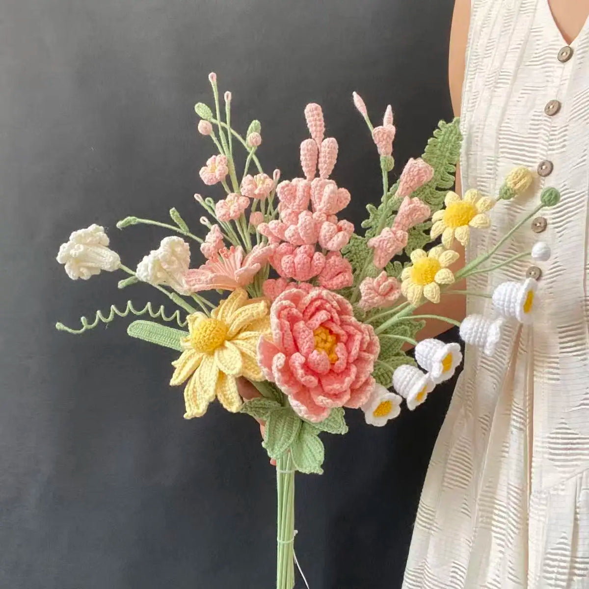 Handmade crochet flower bouquet featuring pink, yellow, and white blooms on a green stem.