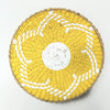 Round woven straw wall decor hanging in yellow and white with a central circular pattern