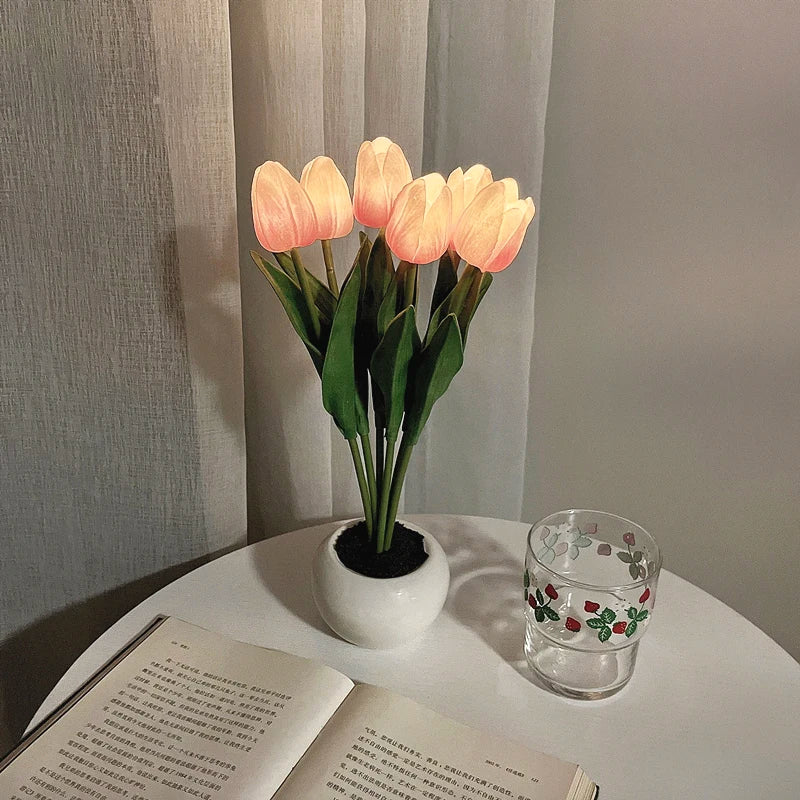 A bouquet of glowing peach-colored tulips in a white ceramic pot used as a night light.