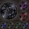 A collection of vintage vinyl record wall clocks in various colors and styles mounted on a brick wall.