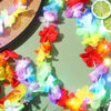 A colorful glow-in-the-dark LED Hawaiian lei necklace is displayed against a green background.