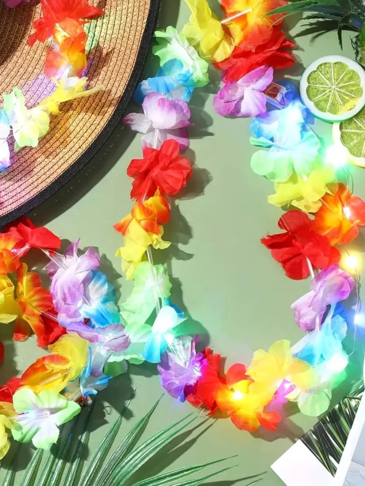 A colorful glow-in-the-dark LED Hawaiian lei necklace is displayed against a green background.